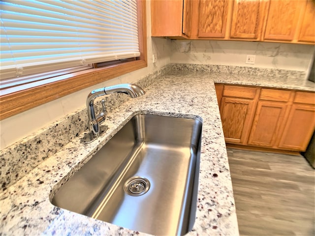 details with sink, light stone countertops, and wood-type flooring