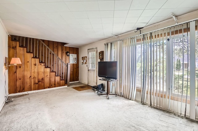 unfurnished living room with carpet floors and wood walls