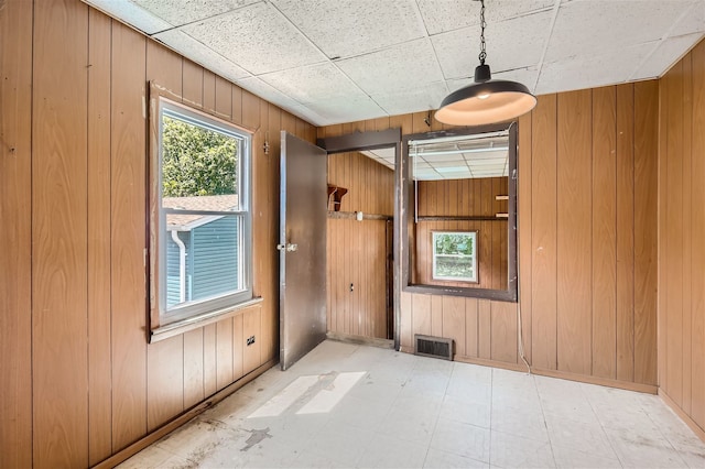 spare room featuring wood walls and a drop ceiling