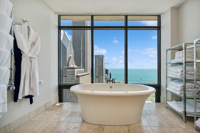 bathroom featuring a tub to relax in, a water view, and expansive windows