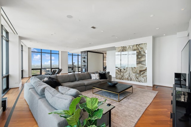 living room featuring light wood-type flooring, floor to ceiling windows, and a healthy amount of sunlight