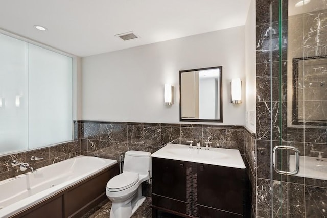 full bathroom with vanity, independent shower and bath, tile walls, and toilet