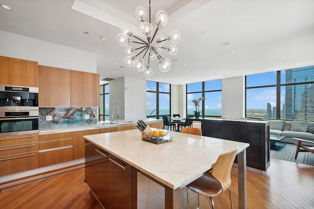 kitchen with backsplash, sink, an inviting chandelier, light hardwood / wood-style floors, and a kitchen island