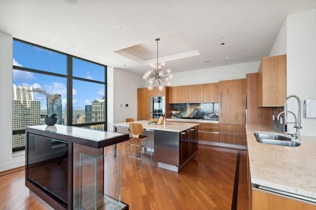 kitchen featuring decorative backsplash, sink, pendant lighting, light hardwood / wood-style flooring, and a center island