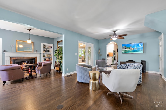 living room with ceiling fan, dark hardwood / wood-style floors, and a brick fireplace