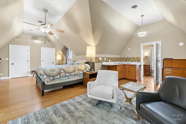 bedroom with light wood-type flooring, vaulted ceiling, connected bathroom, and ceiling fan