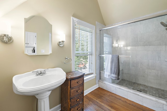 bathroom featuring lofted ceiling, hardwood / wood-style floors, and a shower with shower door