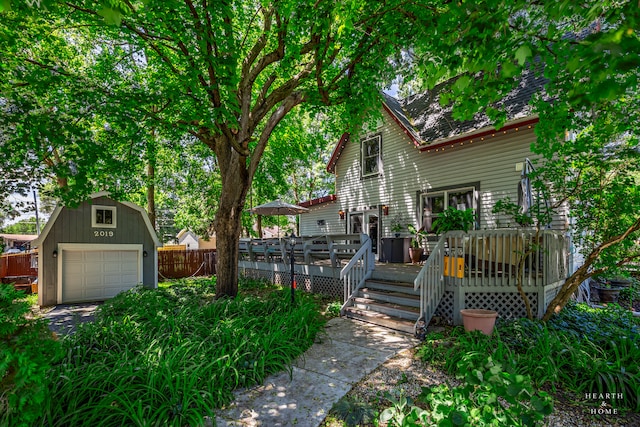 back of house featuring an outdoor structure, a garage, and a wooden deck