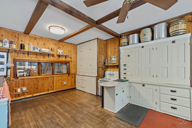 kitchen with wooden walls, beamed ceiling, white cabinetry, dark hardwood / wood-style floors, and ceiling fan