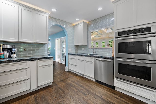 kitchen featuring dark wood-type flooring, stainless steel appliances, white cabinetry, and tasteful backsplash