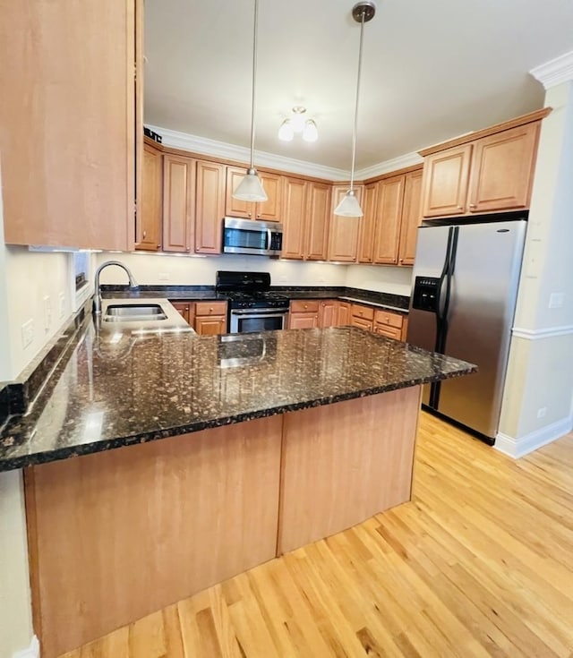 kitchen with kitchen peninsula, ornamental molding, stainless steel appliances, sink, and decorative light fixtures