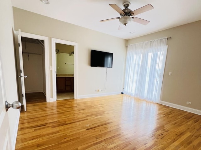 interior space featuring a walk in closet, ensuite bath, ceiling fan, light hardwood / wood-style flooring, and a closet