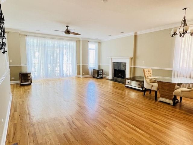 unfurnished living room with ceiling fan with notable chandelier, light hardwood / wood-style floors, ornamental molding, and a tile fireplace