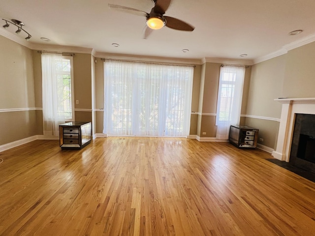 unfurnished living room with a healthy amount of sunlight, light wood-type flooring, and crown molding