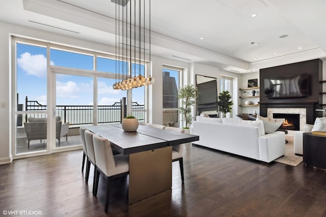 dining area featuring a high end fireplace, a raised ceiling, and dark hardwood / wood-style floors