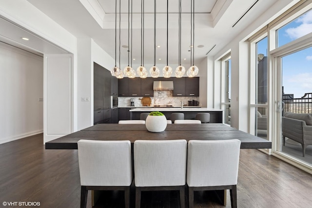 dining space with dark wood-type flooring, crown molding, and a raised ceiling