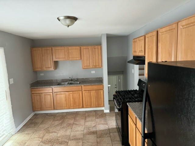 kitchen with light brown cabinetry, black appliances, sink, and light tile patterned floors