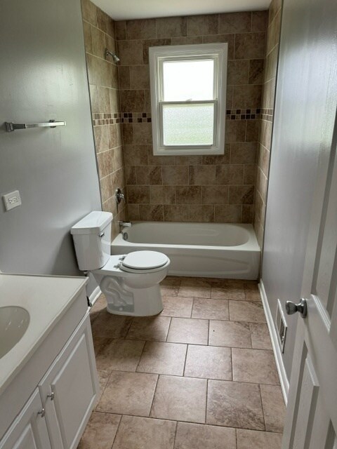 full bathroom with vanity, tiled shower / bath, and toilet