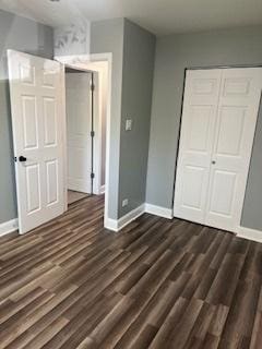 unfurnished bedroom featuring a closet and dark wood-type flooring