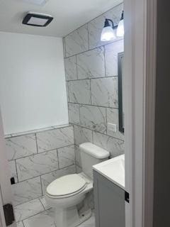 bathroom featuring tile walls, toilet, and vanity