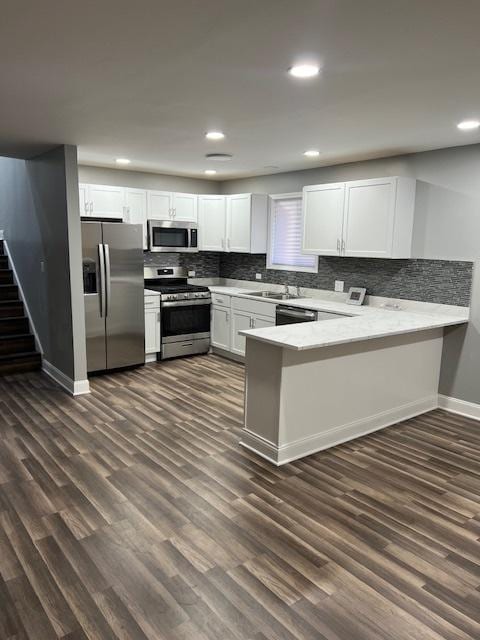 kitchen featuring kitchen peninsula, appliances with stainless steel finishes, white cabinetry, and dark hardwood / wood-style floors