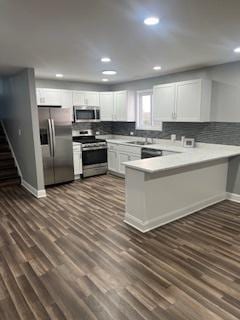 kitchen featuring kitchen peninsula, appliances with stainless steel finishes, white cabinetry, and dark hardwood / wood-style floors