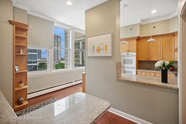 kitchen featuring tasteful backsplash, multiple ovens, dark wood-type flooring, a baseboard heating unit, and ornamental molding