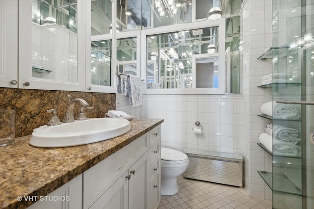 bathroom with toilet, vanity, tile walls, and tile patterned floors