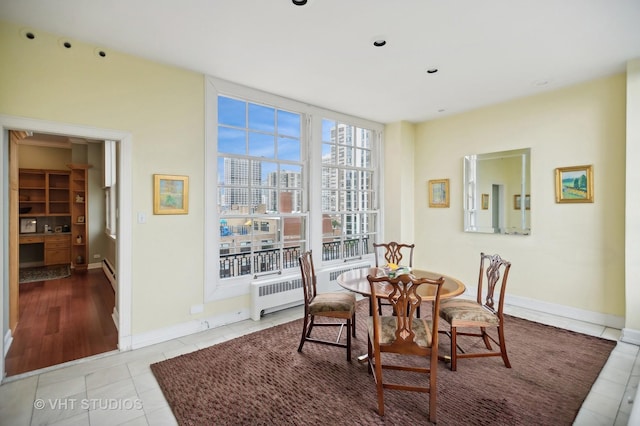 dining space with baseboards, radiator, light tile patterned flooring, and a city view