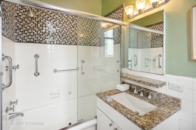 bathroom featuring vanity, combined bath / shower with glass door, decorative backsplash, and tile walls