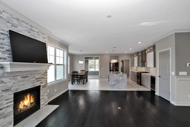 unfurnished living room featuring a stone fireplace, tile patterned flooring, crown molding, beverage cooler, and a notable chandelier