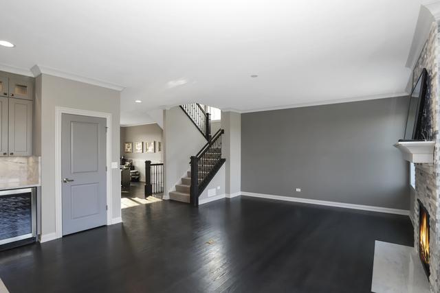 living area with stairway, baseboards, a stone fireplace, and crown molding