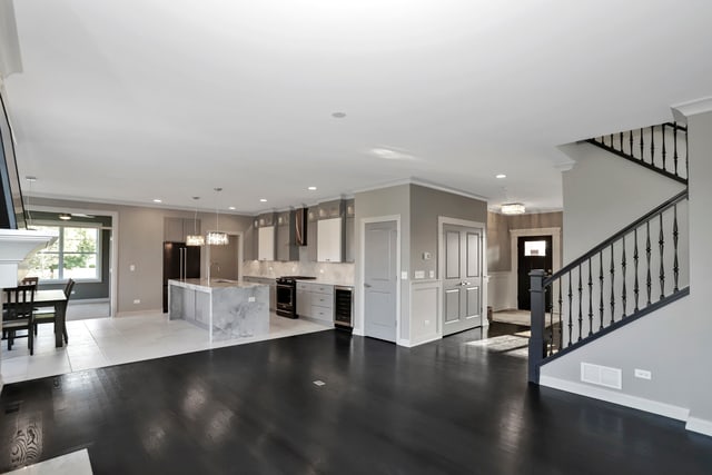 kitchen with a center island with sink, hanging light fixtures, decorative backsplash, beverage cooler, and hardwood / wood-style flooring