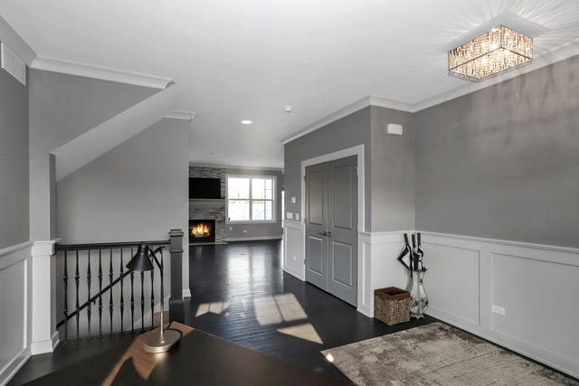 entryway featuring an inviting chandelier, a fireplace, crown molding, and dark hardwood / wood-style floors