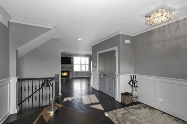 hallway with wood finished floors, crown molding, an upstairs landing, and wainscoting