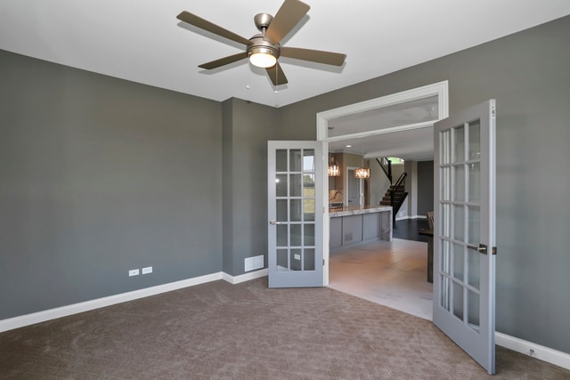 unfurnished room featuring dark colored carpet, ceiling fan, and french doors