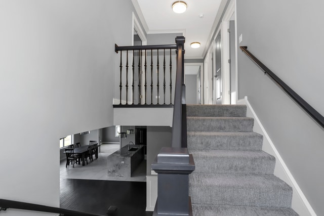 stairs with hardwood / wood-style flooring and ornamental molding