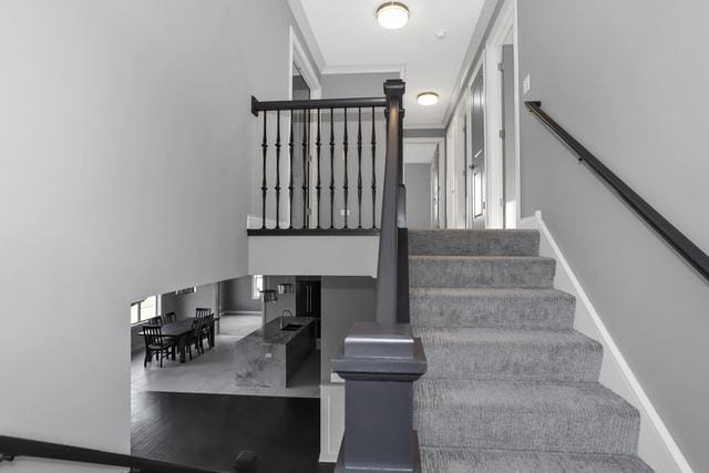 stairway with a high ceiling, wood finished floors, and baseboards