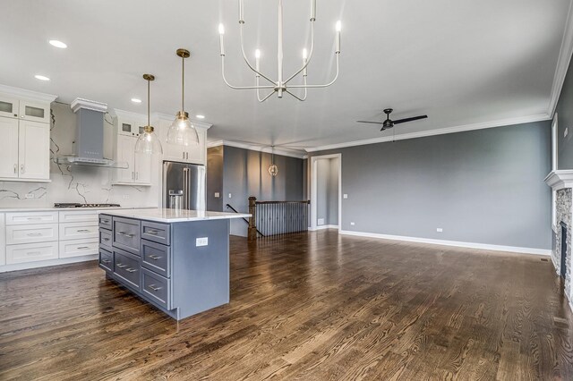 kitchen with ornamental molding, stainless steel appliances, light countertops, white cabinets, and dark wood-type flooring