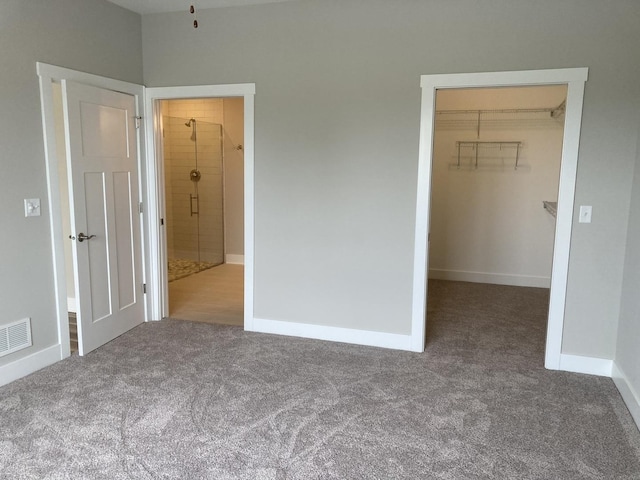 unfurnished bedroom with carpet flooring, a walk in closet, and a closet