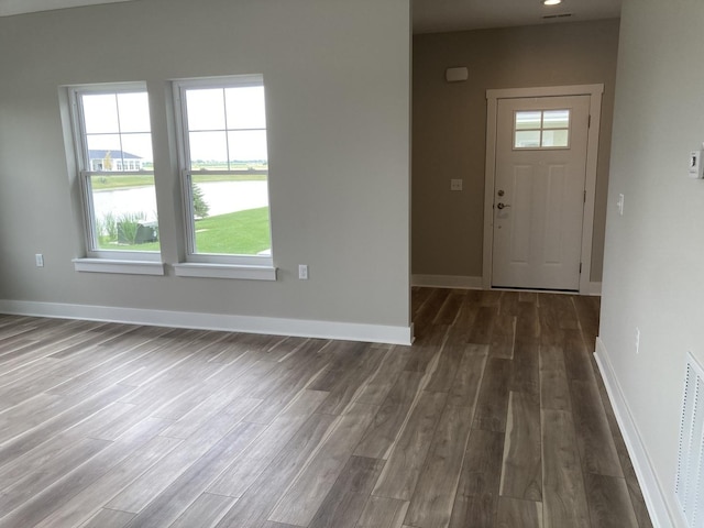 entrance foyer with dark hardwood / wood-style flooring and a water view