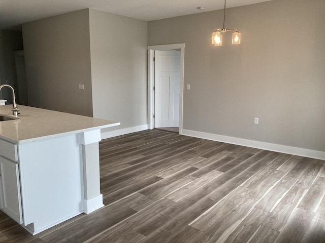 kitchen with dark wood-type flooring, an inviting chandelier, sink, hanging light fixtures, and white cabinetry