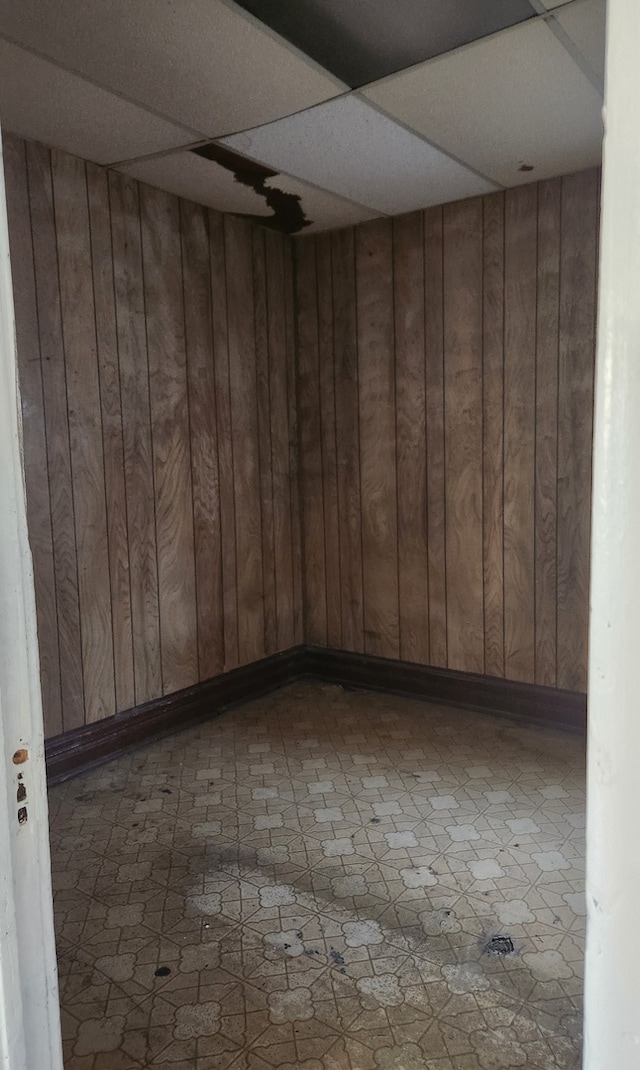 unfurnished room with a paneled ceiling and wooden walls