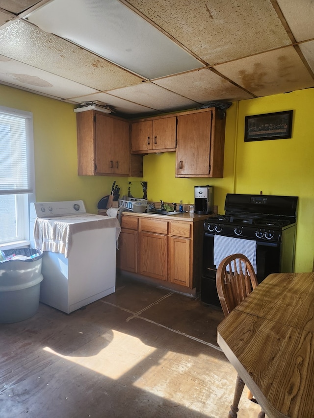 kitchen featuring sink, black range with gas cooktop, a drop ceiling, and washer / dryer