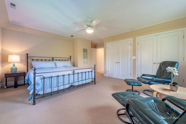 carpeted bedroom with ceiling fan and two closets