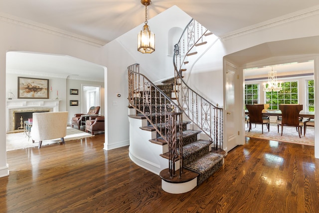 stairs featuring hardwood / wood-style flooring, ornamental molding, and a chandelier