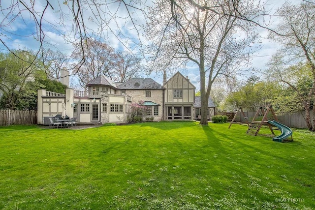 rear view of property with a patio area, a playground, and a yard