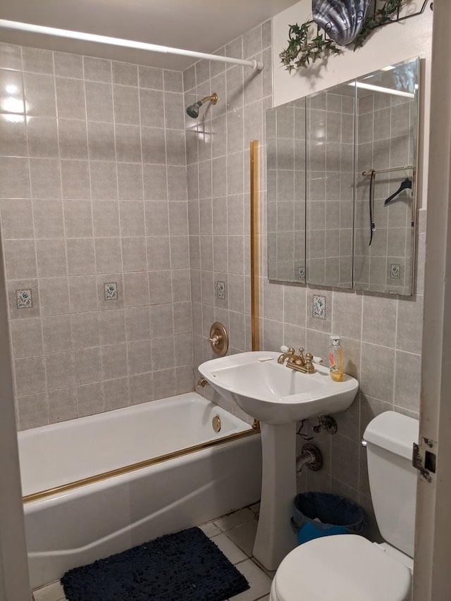 bathroom featuring tile walls, tiled shower / bath combo, tile patterned floors, and toilet