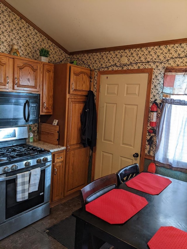 kitchen with dark tile patterned floors, ornamental molding, vaulted ceiling, and stainless steel range with gas stovetop