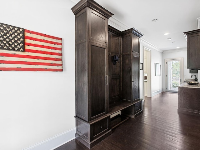 mudroom featuring baseboards, dark wood-type flooring, crown molding, a sink, and recessed lighting